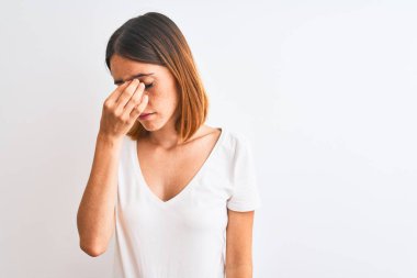 Güzel kızıl saçlı kadın, izole edilmiş arka planda günlük beyaz tişört giyiyor. Burun ve gözler sürtünüyor, yorgunluk ve baş ağrısı hissediyor. Stres ve hüsran kavramı.