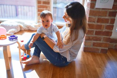Güzel öğretmen ve bebek anaokulunda bir sürü oyuncakla oynuyorlar.