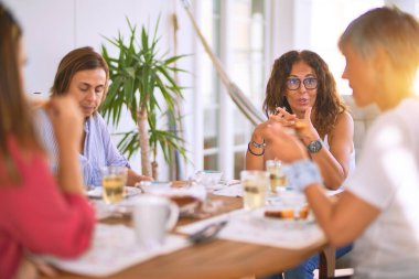 Genç ve güzel bir kız mutlu ve kendinden emin bir şekilde terasta oturmuş bir fincan kahve içiyor.