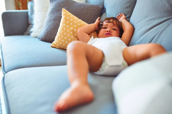 Güzel yürümeye başlayan çocuk kız kanepede yatan beyaz bodysuit giyiyor