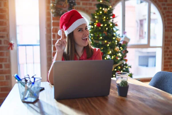 Noel 'de Noel Baba şapkası takmış, dizüstü bilgisayarla çalışan güzel bir kadın başarılı bir fikri işaret ediyor. Heyecanlı ve mutlu. Bir numara..