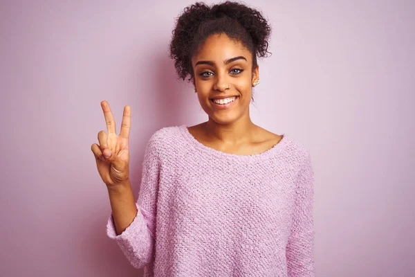 身穿冬季毛衣的年轻非洲裔美国女人站在孤立的粉色背景上 带着自信和快乐的笑容 用手指指了指二号 — 图库照片