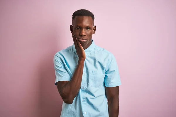 アフリカ系アメリカ人男性身に着けています青カジュアルシャツ上に立って隔離されたピンクの背景考え方疲れていると退屈でうつ病問題で交差腕 — ストック写真