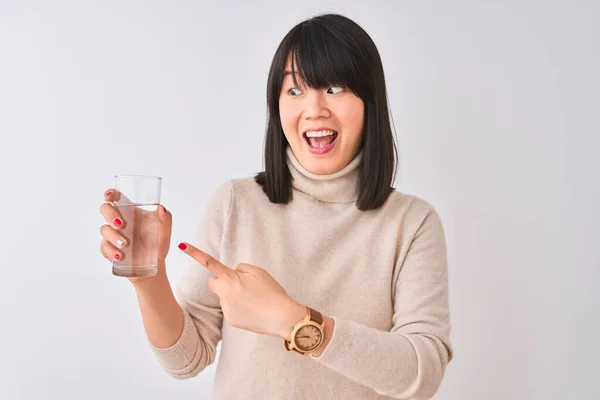 年轻美丽的中国女人 手里拿着一杯水 站在与世隔绝的白色背景上 非常高兴地用手和手指指指点点 — 图库照片
