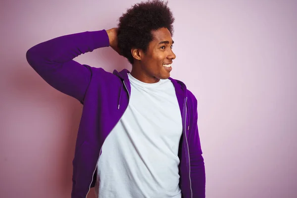 身穿紫色运动衫的年轻的美国黑人男子站在孤立的粉色背景上 自信地微笑着 手举着手触摸着头发 显得迷人而时尚 — 图库照片