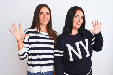 İzole edilmiş beyaz arka plan üzerinde duran gündelik giysiler giyen genç ve güzel kadınlar on numaralı parmaklarıyla işaret ederken kendinden emin ve mutlu bir şekilde gülümsüyorlar..