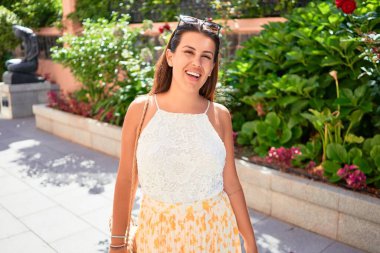 Güneşli bir yaz gününde yeşil parkta mutlu ve neşeli gülümseyen güzel bir kadın.