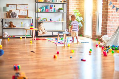 Anaokulunda bir sürü oyuncakla bekleyen güzel bir çocuk.