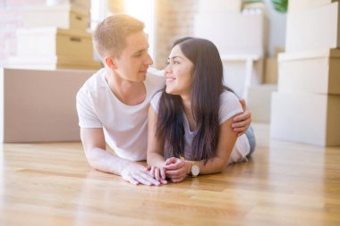 Genç güzel çift karton kutular etrafında yeni evde yatarken