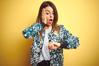 Sarı arka plan üzerine sıradan bir ceket giyen genç ve güzel bir kadın. Endişeli saatlere bakıyor, geç kalmaktan korkuyor.