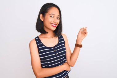 İzole edilmiş beyaz arka plan üzerinde duran çizgili tişört giyen genç Çinli kadın yüzünde kocaman bir gülümsemeyle kameraya el ve parmak ile bakıyor..