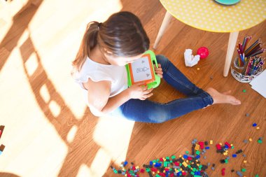 Anaokulundaki oyuncakların etrafında dijital tahta kullanarak sevimli bebek çizimi