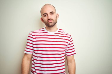 Sakallı, beyaz izole edilmiş arka planda sıradan kırmızı tişörtlü genç, kel bir adam havada öpücük sallayan kameraya bakıyor ve çok güzel ve seksi. Aşk ifadesi.