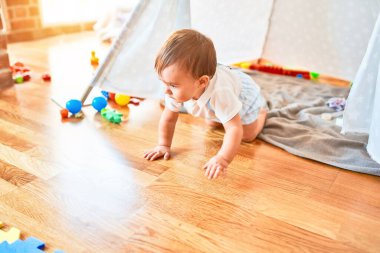 Anaokulunda bir sürü oyuncakla oynayan sevimli bir çocuk.