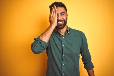 Genç Hintli iş adamı zarif bir gömlek giyiyor. İzole edilmiş beyaz arka planda duruyor. Bir gözünü eliyle kapatıyor..