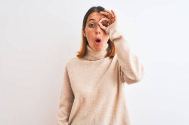 Kış balıkçı yaka kazak giyen güzel, kızıl saçlı bir kadın izole edilmiş arka planda şaşkın şaşkın hareketler yapıyor. İnançsız ifade.