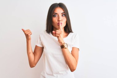 İzole edilmiş beyaz arka plan üzerinde gündelik tişört giyen genç ve güzel bir kadın sessiz olmak istiyor. Sessizlik ve gizli konsept.
