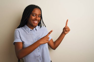 Genç Afrikalı Amerikalı kadın çizgili tişört giyiyor. İzole edilmiş beyaz arka planda duruyor. Gülümsüyor ve kameraya bakıyor..