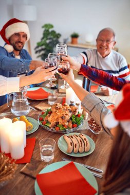 Güzel bir aile Noel Baba şapkası takıyor ve mutlu ve kendinden emin gülümsüyor. Kızarmış hindi yemek evde Noel 'i kutlamak için bir bardak şarapla kadeh kaldırmak.