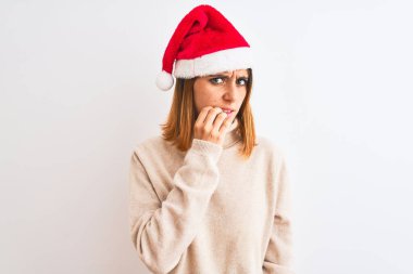 Güzel kızıl saçlı kadın, izole edilmiş arka planda noel şapkası takıyor. Ağız ısıran elleri yüzünden gergin ve gergin görünüyor. Endişe sorunu.