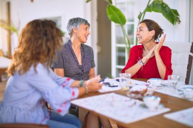 Orta yaşlı kadınlarla buluşup, öğle yemeği yiyip, kahve içiyorlar. Olgun arkadaşlar mutlu bir şekilde gülümsüyor. Güneşli bir günde evde akıllı telefon kullanıyorlar.
