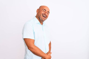 Orta yaşlı yakışıklı bir adam, sıradan bir tişört giymiş, izole edilmiş beyaz arka plan üzerinde duruyor, yüzünde gülümseme, doğal bir ifade ile yan yana bakıyor. Kendinden emin gülen.