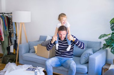 Genç ve yakışıklı baba, güzel bebeğini omuzlarında tutuyor.