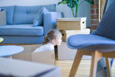 Güzel yürümeye başlayan çocuk kız yeni evde kutuları ile oynarken