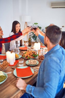 Mutlu ve kendinden emin bir şekilde gülümseyerek tanışan güzel bir grup insan. Kızarmış hindi yemek ve evde Şükran Günü 'nü kutlamak için bir bardak şarapla kadeh kaldırmak.