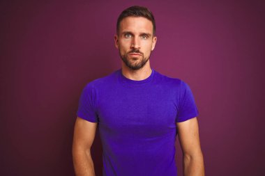 Leylak izole arka plan üzerine günlük mor tişört giyen genç adam yüzünde ciddi bir ifadeyle rahatlamış. Basit ve doğal bir şekilde kameraya bakıyorsun..