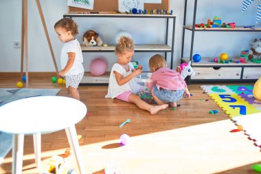 Anaokulunda bir sürü oyuncakla oynayan sevimli çocuklar.