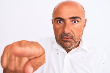 Orta yaşlı, şık gömlekli, soyutlanmış beyaz arka plan üzerinde duran yakışıklı bir adam kamerayı işaret ediyor ve sen, el işareti, ön taraftan pozitif ve kendinden emin bir hareket.