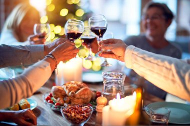 Aile ve arkadaşlar Noel arifesini geleneksel yemek ve dekorasyonla birlikte evde yemek yiyorlar. Hep birlikte masaya oturuyorlar.