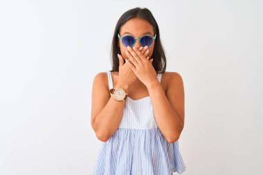 İzole edilmiş beyaz arka planda çizgili elbise ve güneş gözlüğü takan genç Çinli kadın yanlışlıkla ağızlarını kapatarak şok geçirdi. Gizli konsept.