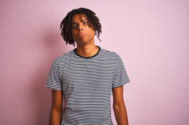 Rasta desenli donanma tişörtlü Afro adam pembe arka planda dikiliyor. Depresyonda ve üzüntüden ağlıyor, ağlıyor ve korkuyor. Üzücü ifade.