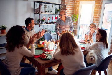 Noel arifesini evde geleneksel yemek ve dekorasyonla kutlayan aile ve arkadaşlar gururlu hindi pişirme gösterisi yapıyorlar.