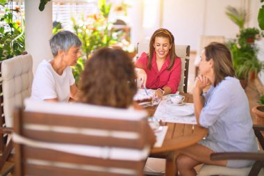 Genç ve güzel bir kız mutlu ve kendinden emin bir şekilde terasta oturmuş bir fincan kahve içiyor.