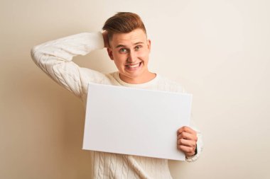 İzole edilmiş beyaz arka planda pankart tutan genç yakışıklı adam elleri başının üstünde, utanç ve şaşkınlık dolu, sinirli ve hayal kırıklığına uğramış bir halde. Hata için korku ve üzüntü.