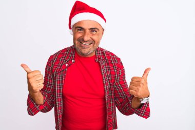 Noel Baba şapkası takan orta yaşlı bir adam izole edilmiş beyaz arka plan başarısı tabelasının üzerinde duruyor. Elleriyle olumlu jest yapıyor, gülümsüyor ve mutlu. Neşeli ifade ve kazanan jest.
