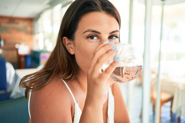 夏休みを楽しむレストランに座っている若い美しい女性水のグラスを飲む — ストック写真