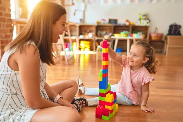 Schöne Lehrerin Und Blondes Kleinkind Bauen Turm Aus Plastikklötzen Kindergarten — Stockfoto