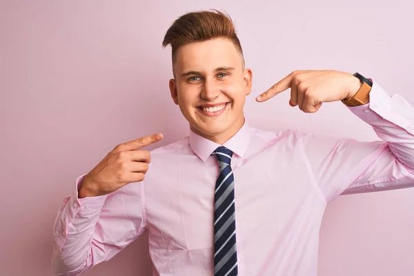 年轻英俊的商人穿着衬衫和领带站在孤立的粉红色背景上 微笑着欢快地展示着 并用手指咬牙切齿 牙齿健康概念 — 图库照片