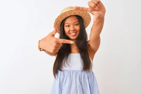 年轻的中国女人穿着条纹衣服 头戴帽子 站在孤独的白色背景上 微笑着 用双手和手指做着幸福的框架 创意和摄影概念 — 图库照片