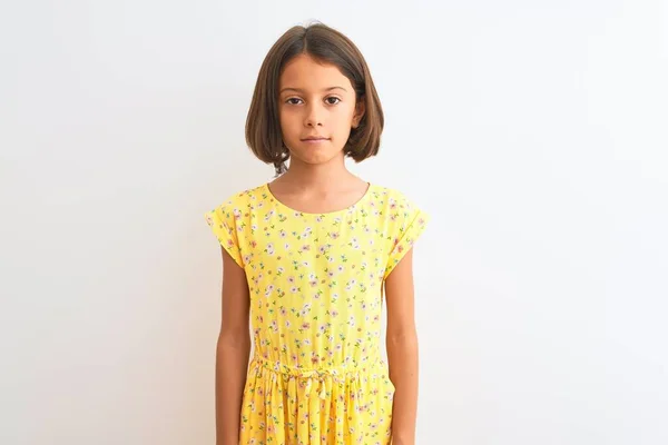 年轻漂亮的小女孩穿着黄色的花衣服站在孤立的白色背景上 脸上带着严肃的表情 简单而自然地看着相机 — 图库照片