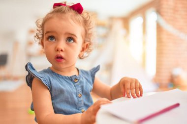 Renkli oyun odasında beyaz güzel bir bebek oyuncaklarla oynuyor. Anaokulunda renkli kalemlerle mutlu ve eğlenceli çizimler..