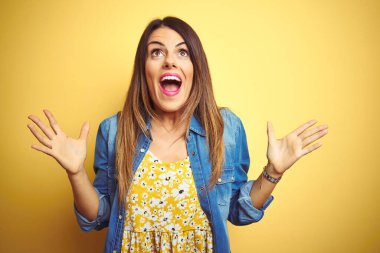 Sarı arka planda duran genç ve güzel bir kadın çılgın ve başarıyı kollarını kaldırıp heyecanla haykırarak kutluyor. Kazanan konsept