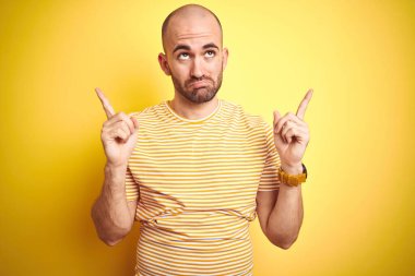 Sakallı, sarı renkli tişörtlü genç, kel bir adam üzgün ve üzgün görünüyor. Mutsuz ve depresif..