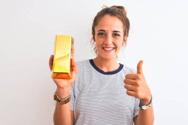 Güzel, kızıl saçlı, altın külçeli genç bir kadın izole edilmiş arka planda mutlu bir şekilde gülümsüyor.