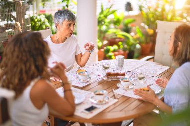 Genç ve güzel bir kız mutlu ve kendinden emin bir şekilde terasta oturmuş bir fincan kahve içiyor.