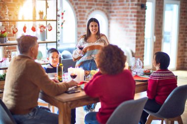 Mutlu ve kendinden emin gülümseyen güzel bir aile. Bir tanesi elinde şarap bardağıyla evde Noel 'i kutlarken konuşuyordu.